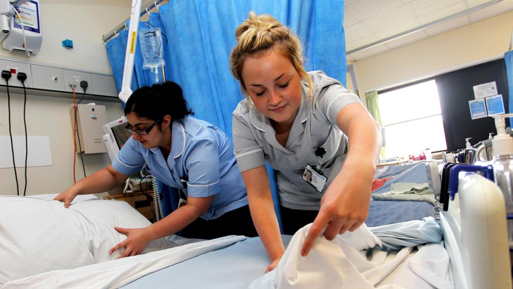Nurses adjusting a patient's bed