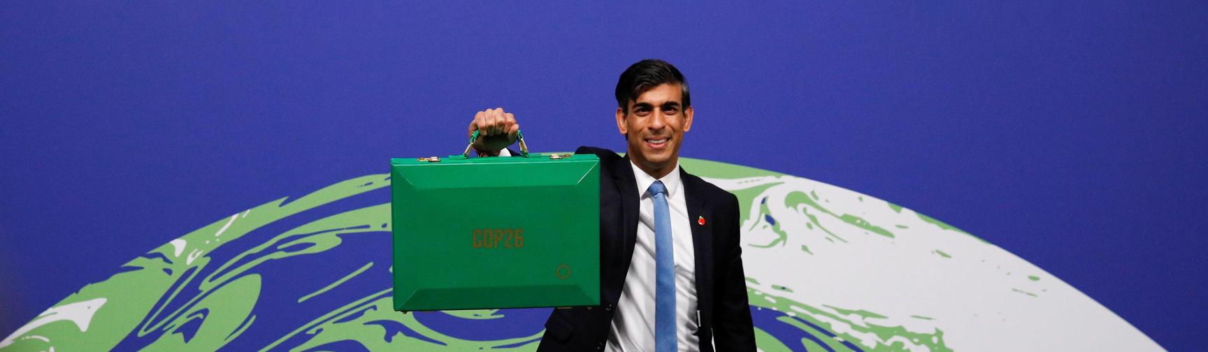 Rishi Sunak at the COP26 conference in Glasgow in 2021. He is holding a green budget briefcase in his hand.