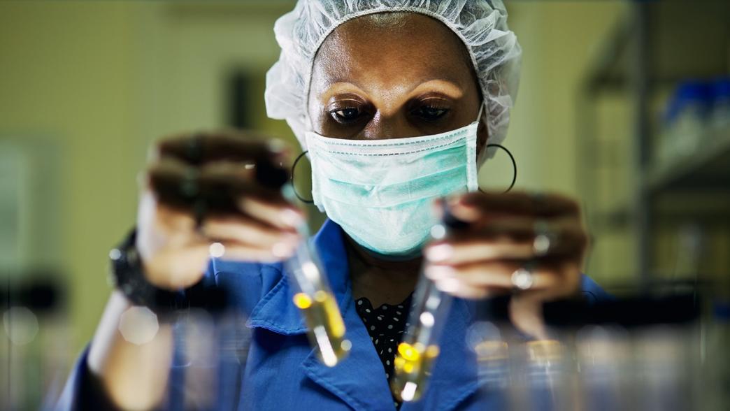 A female scientist in the lab examining two test tubes