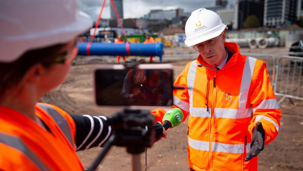 Andy Street, the mayor for the West Midlands, in a high viz jacket and hard hat. He is filming a piece to camera.