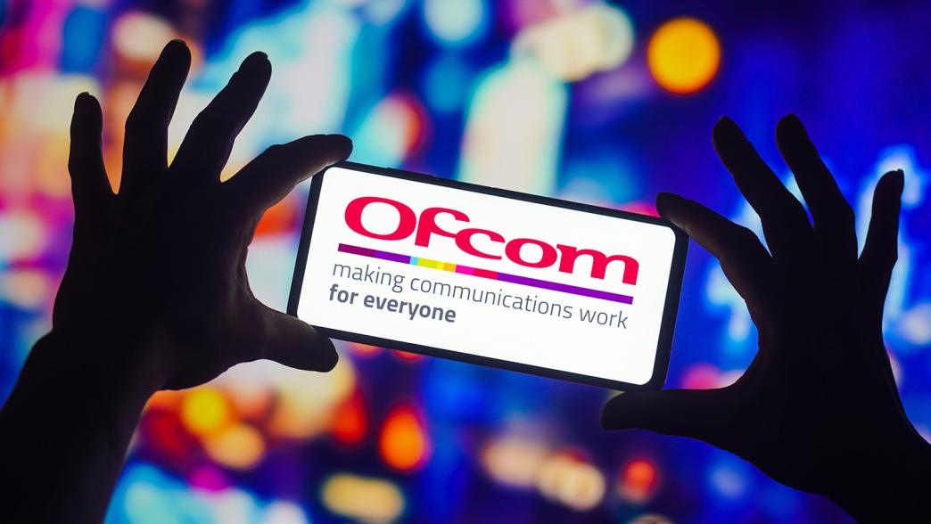 Someone holding a smart phone with the Ofcom logo displayed on screen.