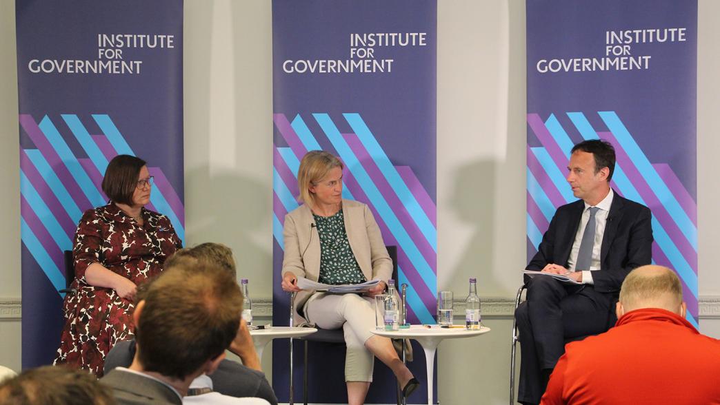 Dame Meg Hillier MP, Dr Hannah White and Alex Chisholm on stage at the IfG. Behind them are three IfG branded branners. 