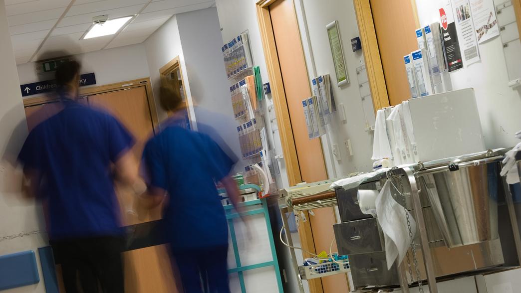 NHS staff walking down a hospital corridor.