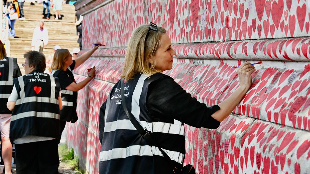 A woman painting on the National Covid Memorial Wall in London.