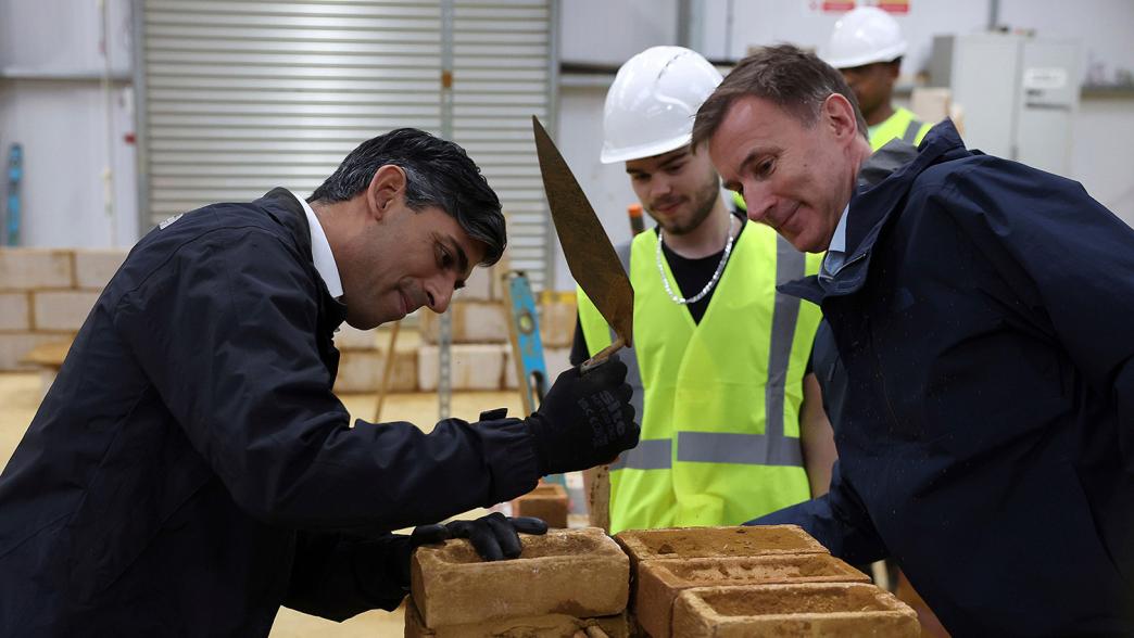 Rishi Sunak and Jeremy Hunt learn how to lay bricks during a visit to a college in north London