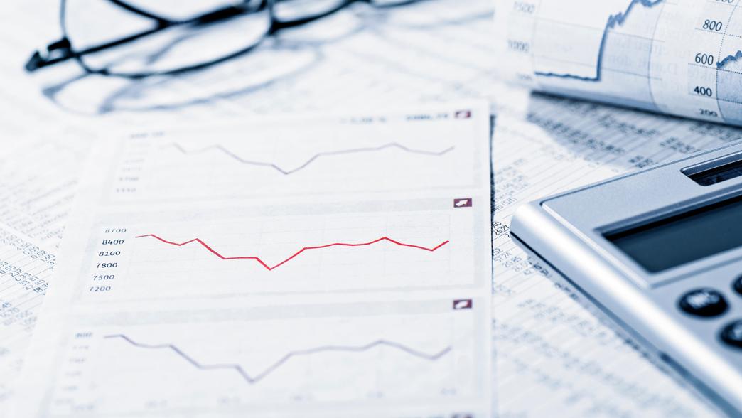 Image of a chart, spreadsheet, and calculator on a desk