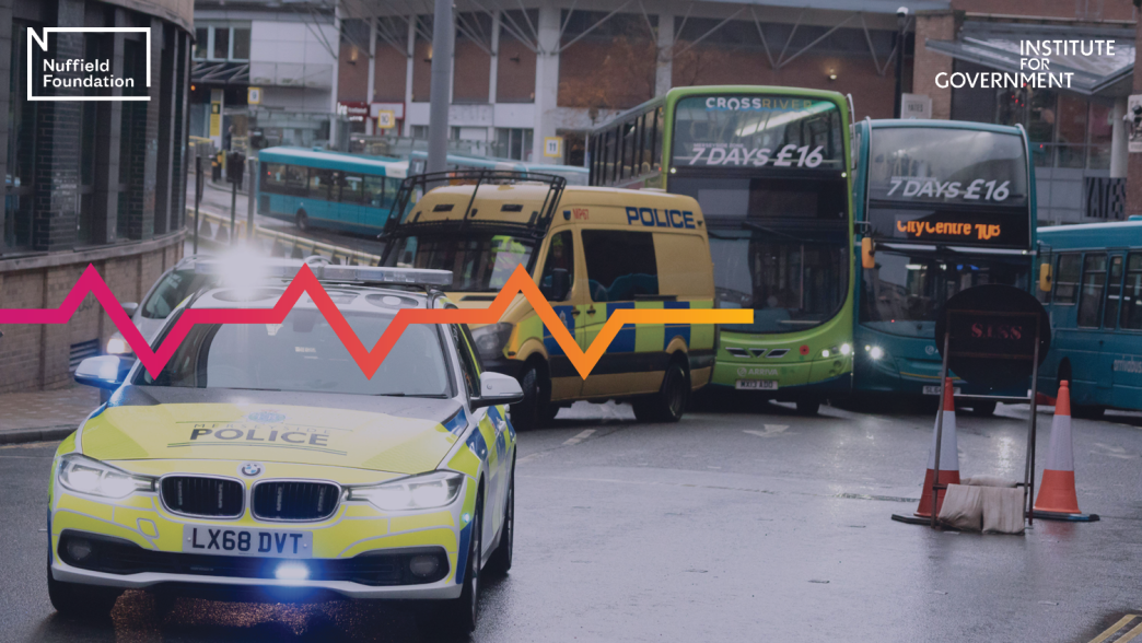 Police cars block the road as a protest moves through the area