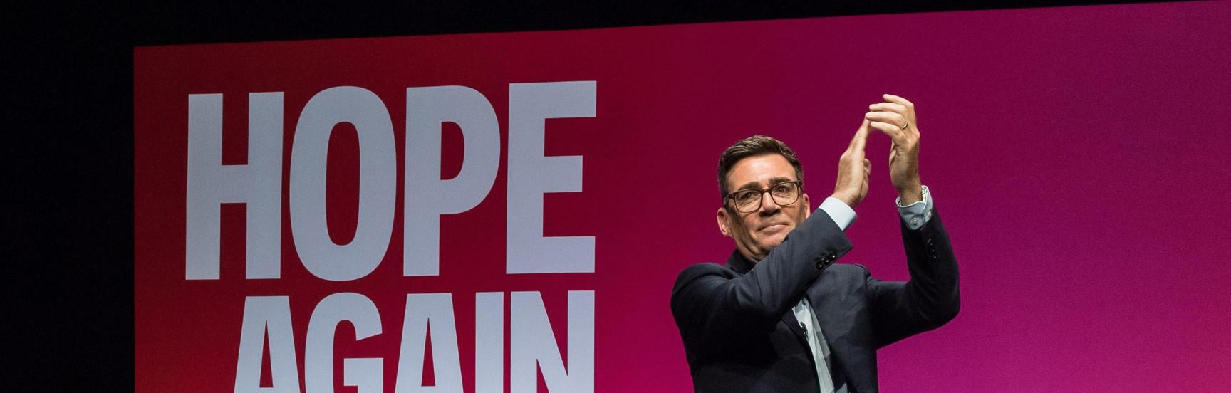 Andy Burnham on stage at the Labour Party Conference. Behind him the screen reads: Hope Again