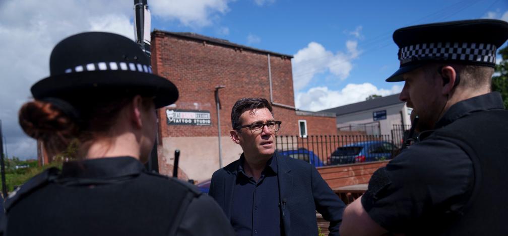 Andy Burnham speaks with police personnel during a campaign visit to the town of Ashton-in-Makerfield before the forthcoming Makerfield by-election