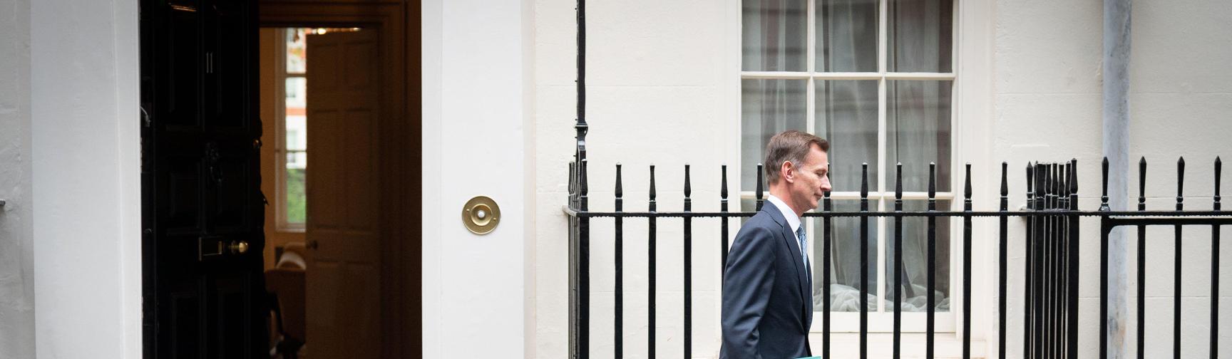 Jeremy Hunt walking down Downing Street with the autumn statement in his hand.