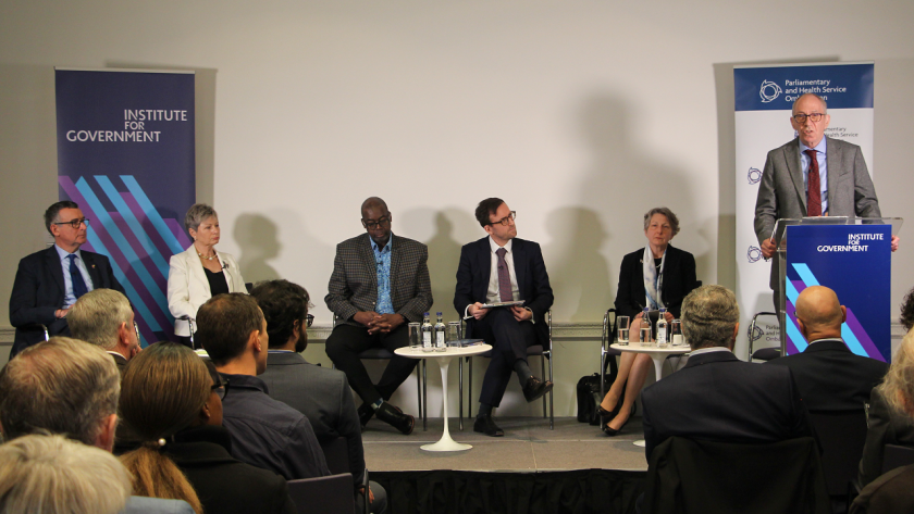 Sir Bernard Jenkin MP, Sandra Verkuyten OBE, Patrick Vernon OBE, Dr Matthew Gill, Rosemary Agnew and Rob Behrens CBE on stage to discuss ombuds reform. Rob Behrens is standing behind a lectern.