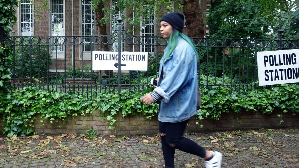 Voter walks to EU Referendum polling station, Islington, London. She is wearing a denim shirt and beanie, and has green hair.